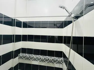 a shower in a bathroom with black and white tiles at T&A Building in Manila