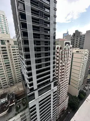 a tall building in a city with tall buildings at Tahanan Studio at Salcedo Skysuites in Manila
