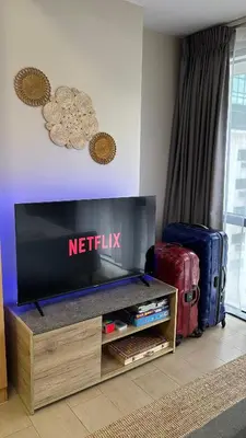a living room with a television and luggage at Tahanan Studio at Salcedo Skysuites in Manila