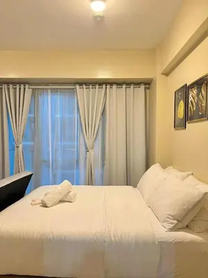 a bedroom with a large white bed with a window at Big Studio Condo Across Manila Airport NAIA T3 WITH WIFI in Manila
