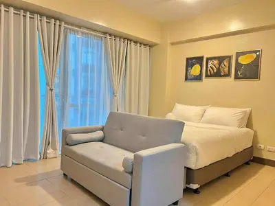 a bedroom with a bed and a couch and a window at Big Studio Condo Across Manila Airport NAIA T3 WITH WIFI in Manila