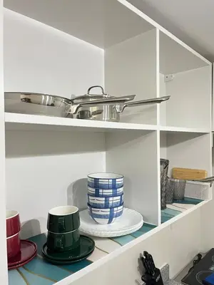a kitchen shelf with dishes and a pan on top at Holly's Place by Motorists Transient House in Biñan