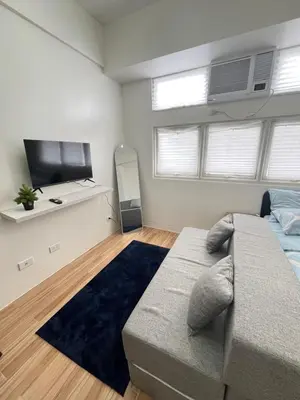 a bedroom with a couch and a flat screen tv at Holly's Place by Motorists Transient House in Biñan