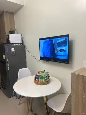 a room with a table and a tv on a wall at Shore 2 Residences - The Grand Haven in Manila