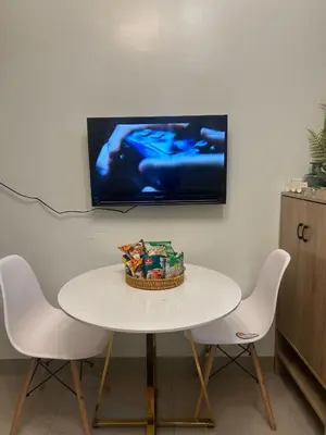 a white table with two chairs and a tv on the wall at Shore 2 Residences - The Grand Haven in Manila