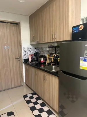 a kitchen with wooden cabinets and a stainless steel refrigerator at Shore 2 Residences - The Grand Haven in Manila