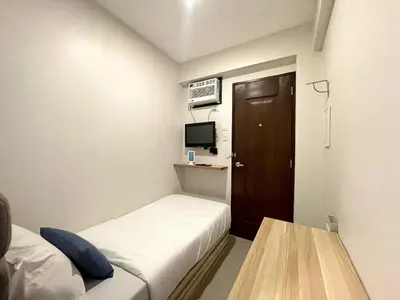 a small hotel room with a bed and a table at airobedz ZOBEL ROXAS- A Value Hotel in Manila