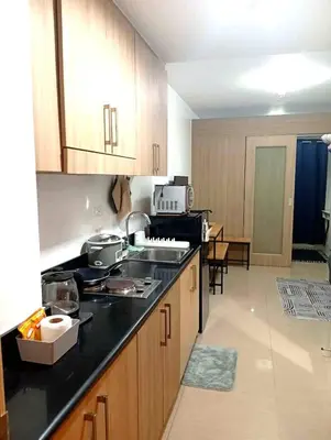 a kitchen with wooden cabinets and a black counter top at Condo MOA Complex Pasay - Shore 1 Tower D Residence - Home away from Home in Manila
