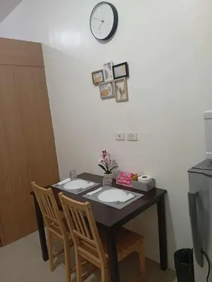 a dining room table with two chairs and a clock on the wall at Condo MOA Complex Pasay - Shore 1 Tower C2 Residence - Home away from Home in Manila