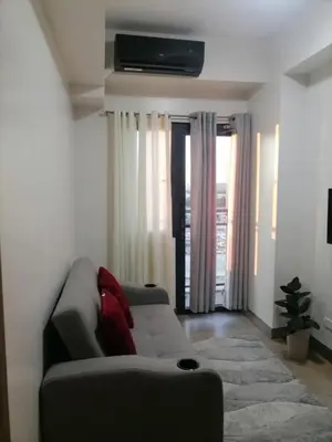 a living room with a couch and a television on the wall at Cozy Staycation Suite at Rossy's Place near in Paranaque in Manila