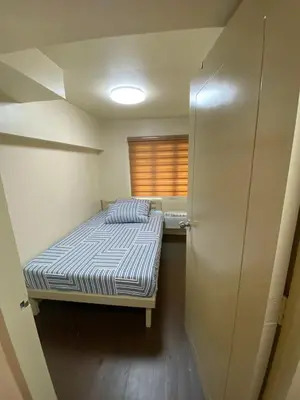 a small bedroom with a bed and a window at Whereabouts Midway Condotel in Manila