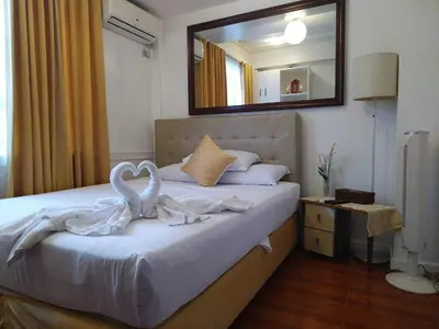 a bedroom with a white bed with a mirror on it at Makati Riverside Inn in Manila