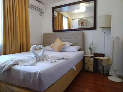 a bedroom with a bed with white sheets and a mirror at Makati Riverside Inn in Manila