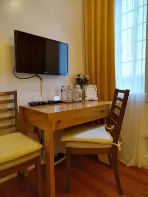 a wooden desk with a television and two chairs at Makati Riverside Inn in Manila