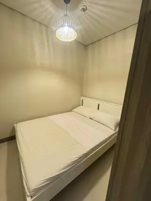 a small bedroom with a white bed with a light at Canadian Suite at Coast Residences Penthouse in Manila
