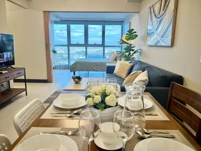 a living room with a table with plates and glasses at Upscale 2BR in Uptown Parksuites with Free Parking in Manila