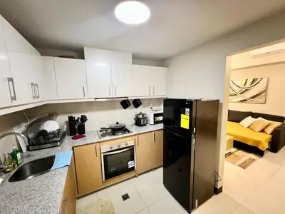 a kitchen with white cabinets and a black refrigerator at Upscale 2BR in Uptown Parksuites with Free Parking in Manila