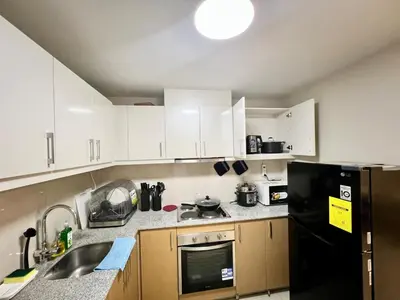 a kitchen with white cabinets and a black refrigerator at Upscale 2BR in Uptown Parksuites with Free Parking in Manila