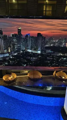 a view of a city skyline at night from a pool at Christine Suites PH at The Gramercy Residences Makati in Manila