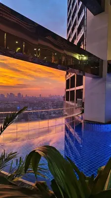 a pool on top of a building with a sunset at Christine Suites PH at The Gramercy Residences Makati in Manila