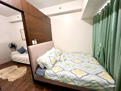 a small bedroom with a bed and green curtains at Skyline Serenity Designer 1BR with Balcony at Air in Manila