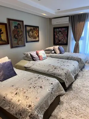 three beds in a room with paintings on the wall at Super cozy Family Villa in Manila