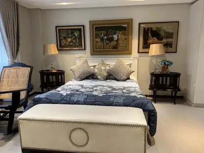 a bedroom with a large bed with paintings on the wall at Super cozy Family Villa in Manila