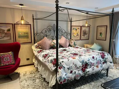 a bedroom with a canopy bed and a red chair at Super cozy Family Villa in Manila