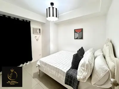 a white bedroom with a bed and a pendant light at Masie Beach Staycation in Manila