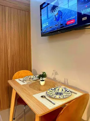 a wooden table with chairs and a television on a wall at Casa Felice at Shore 2 Residences in Manila