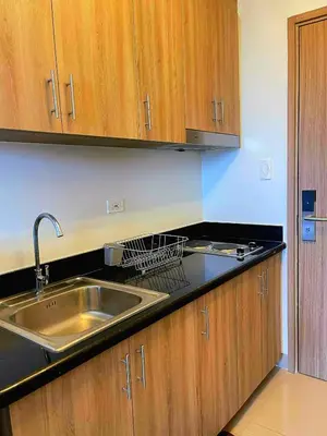 a kitchen with a sink and wooden cabinets at Casa Felice at Shore 2 Residences in Manila