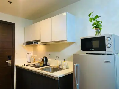 a kitchen with a sink and a microwave on top of a refrigerator at Tropical Chic Escape With City lights View- Modern Scandi in Manila