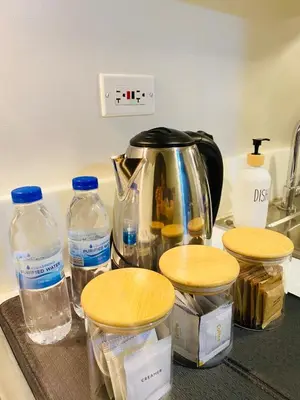 a kitchen counter with bottles of water and a tea kettle at Tropical Chic Escape With City lights View- Modern Scandi in Manila