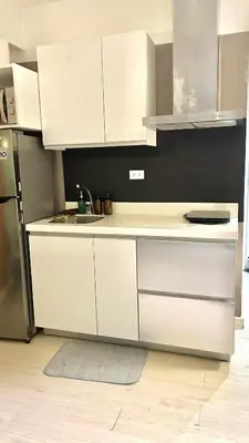 a kitchen with white cabinets and a stainless steel refrigerator at Azure Skyline Pad in Manila