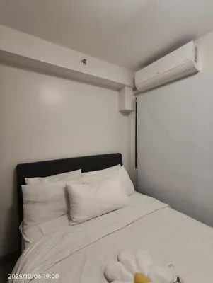 a white bed with white pillows and a heater at Shore Residences MOA in Manila