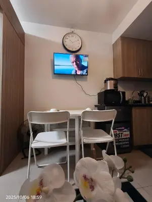 a kitchen with a table and two chairs and a clock at Shore Residences MOA in Manila