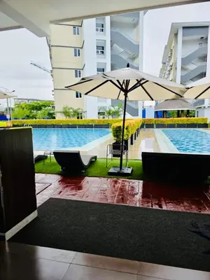 a swimming pool with an umbrella next to a building at Condo Stay Near SM City Santa Rosa Mall in Ibaba