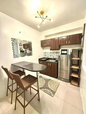 a kitchen with a table and chairs and a refrigerator at Cozy Cabin by JLS Near Venice Grand Canal Mall in Manila