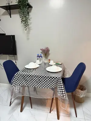 a dining table with a black and white table cloth and blue chairs at Monarch Parksuites 1BR with balcony in Manila