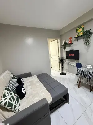a bedroom with a bed and a table and a television at Monarch Parksuites 1BR with balcony in Manila