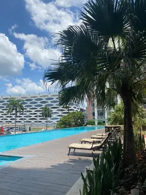 a pool with benches and a palm tree in front of a building at Monarch Parksuites 1BR with balcony in Manila