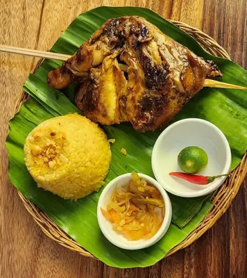 a plate of food with chicken and corn on a banana leaf at Best Value-Beautiful 1BR in the Heart of Makati w WiFi, washer-dryer, pool & gym in Manila