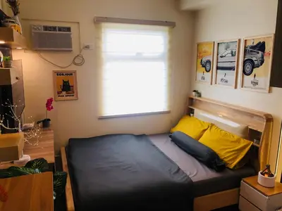 a small bedroom with a bed with a window at Dos Staycation Urban Deca Cubao in Manila