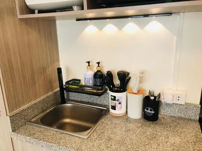 a kitchen counter with a stainless steel sink and utensils at Dos Staycation Urban Deca Cubao in Manila