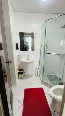 a bathroom with a shower and a sink and a red rug at Mezza Residences in Manila