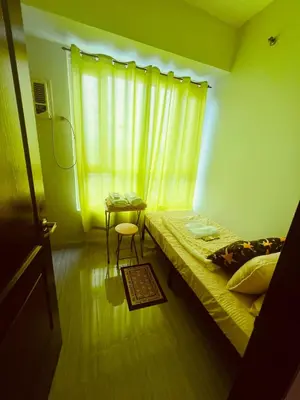 a bedroom with a bed and a table and a window at Mezza Residences in Manila