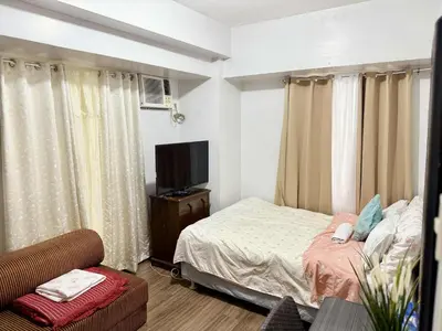 a bedroom with a bed and a tv and a couch at 1BR Minimalist Family Staycation in Manila