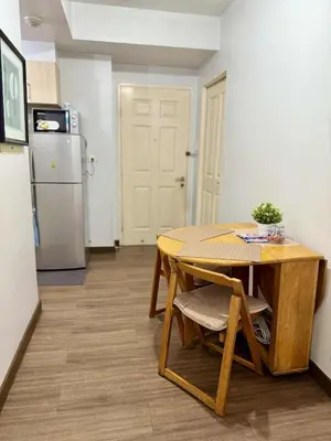 a small kitchen with a table and a refrigerator at 1BR Minimalist Family Staycation in Manila
