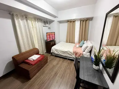 a bedroom with a bed and a table and a chair at 1BR Minimalist Family Staycation in Manila