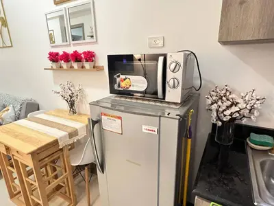 a kitchen with a microwave on top of a refrigerator at Japan Vibe Shaw MRT Train EDSA 1BR with Veranda Netflix Internet Pool View in Manila